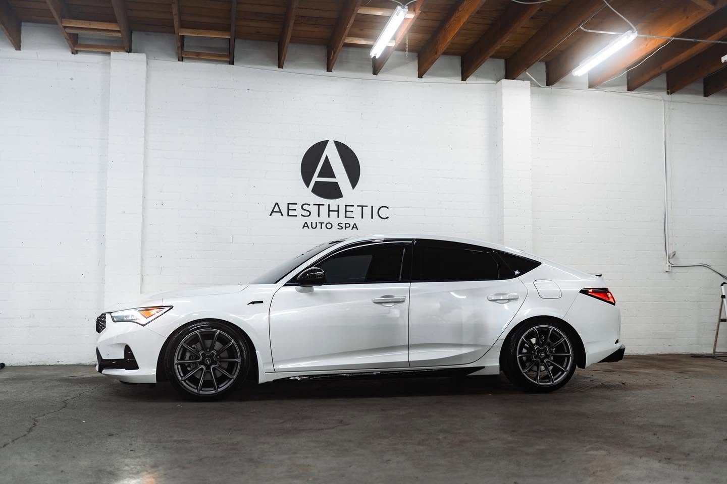 White Acura Integra with fully tinted side glass inside the Aesthetic Auto Spa facility